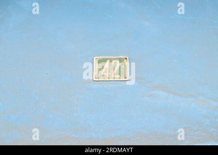 Number 42, forty-two, small plate on a large blue background. Stock Photo