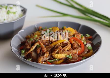 Baby corn chilly served along with butter rice with spring onions. An Indo Chinese dish with crisp fried baby corn in a spicy sauce with sauteed onion Stock Photo
