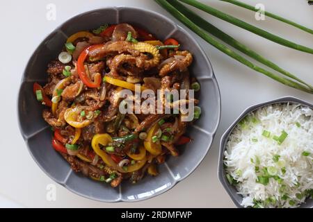 Baby corn chilly served along with butter rice with spring onions. An Indo Chinese dish with crisp fried baby corn in a spicy sauce with sauteed onion Stock Photo