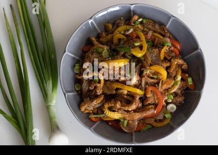 Baby corn chilly. An Indo Chinese dish with crisp fried baby corn in a spicy sauce with sauteed onions and bell peppers. Shot on white background Stock Photo