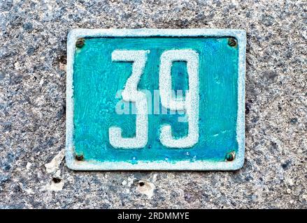 Number 39, thirty-nine, light blue plate on gray stone surface. Stock Photo