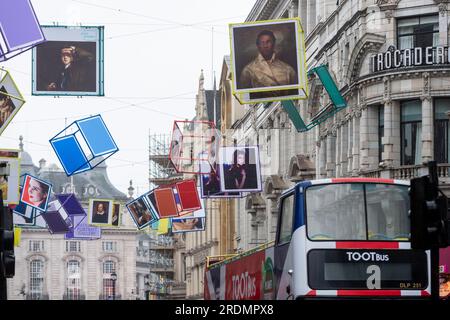 London, UK.  22 July 2023.  Decorated cubes hang overhead in Coventry Street, just off Leicester Square, ahead of ‘Art of London’s Summer Season 2023: The Art of Entertainment’.  Portraits of famous cultural icons, including Elton John, Olivia Colman, Judi Dench, William Shakespeare, Saoirse Ronan, Dusty Springfield and Kate Bush, can be seen on the cubes.  The public art initiative is called ‘Art Reframed’, and developed in partnership with the recently reopened National Portrait Gallery (NPG).  Credit: Stephen Chung / Alamy Live News Stock Photo