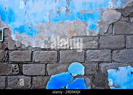 Beautiful aged wall with brickwork patterns, crumbling plaster and flaking paint, beauty of old decaying architecture. Stock Photo