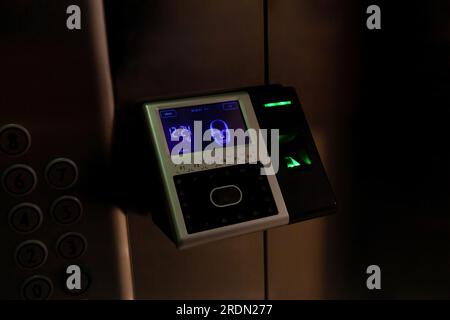 The fingerprint access control terminal with face recognition function installed in the elevator of the business center monitors attendance in real ti Stock Photo