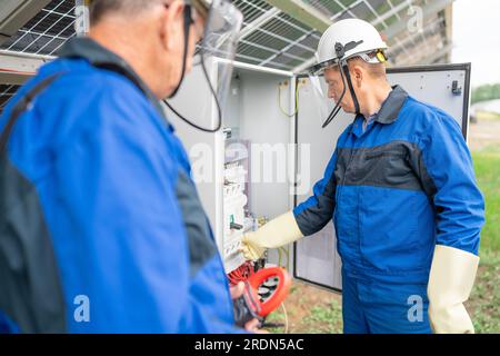 Two Service Engineers or electrician working on checking transformer site and solving problem for green energy solar power plant operation. Technician Stock Photo