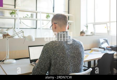 Man in glasses working in office on laptop. Stock Photo