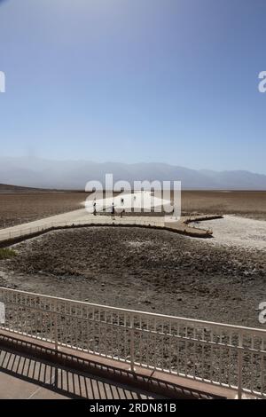 Tourists walking along the boardwalk and onto the sand flats at Badwater Basin in Death Valley National Park, California, USA, on a hazy summer day Stock Photo