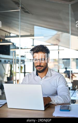 Busy young Latin business man looking at laptop using computer at work. Stock Photo