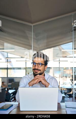 Young Latin business man working in office looking away. Vertical Stock Photo