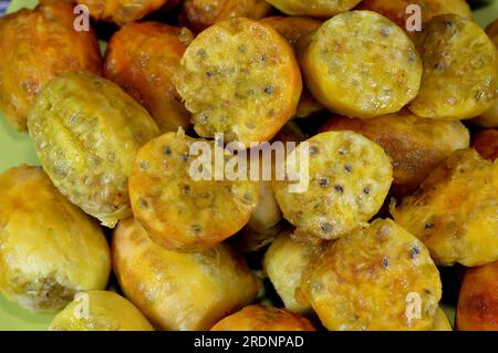 A pile of peeled fresh prickly pear fruit in a plate isolated on wooden background, Opuntia, commonly called prickly pear, Barbary fig, tuna fruit, sa Stock Photo