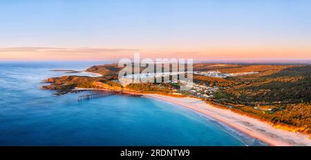 Scenic aerial panoramic view of Cathrenie Hill bay Middle Camp beach with historic jetty at sunrise. Stock Photo