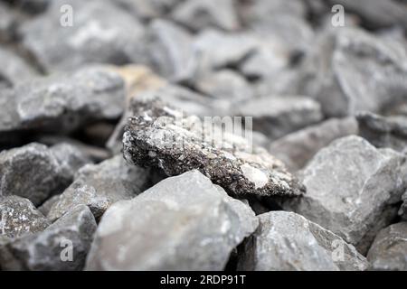 Close up of rough textured black and white rock among similar rocks in natural light Stock Photo