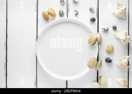White plate with seashells on white wooding background, wallpaper Stock Photo