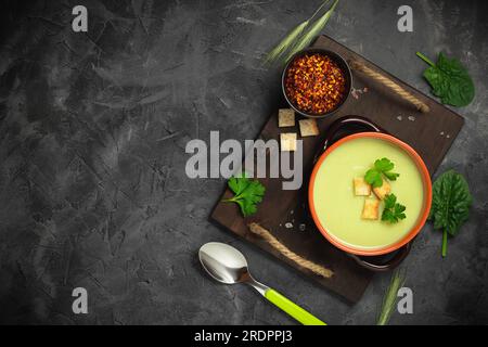 Healthy asparagus soup in a bowl over dark wooden cutting board, concrete background. Stock Photo