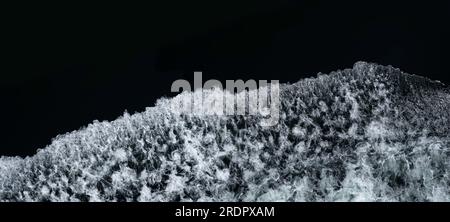 Bow waves of a ship with foam on the water of the black sea. Splashing water, seen from above. Widescreen image Stock Photo