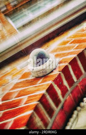 Round surveillance cameras on a curved red brick wall Stock Photo