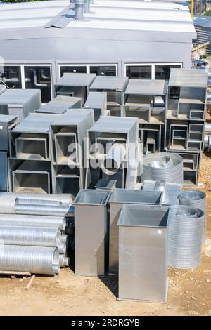 Various sheet metal air ducts in stock for installation in a building under construction. Ventilation system for large buildings. Ventilation pipes ma Stock Photo