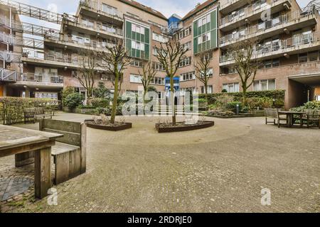 a courtyard with benches and trees in the middle part of an apartment complex that looks like it's from around the world Stock Photo