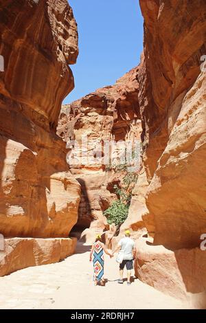 Senior couple walk hand in hand down Al-Siq towards the entrance to the ancient Nabatean City of Petra Stock Photo