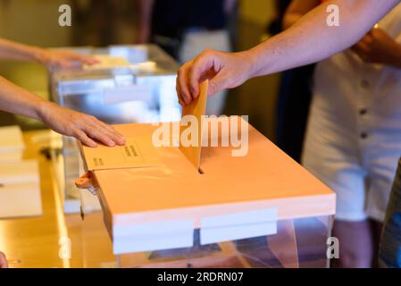 Barcelona, Spain. 23rd July, 2023. In this close up a hand is seen putting the electoral card in a voting ballot at a polling station during Spain's 2023 general elections. Early elections, held for the first time during summer season, were called by President Pedro Sanchez and see a left wing coalition comprised by the PSOE and Sumar parties challenged by the right wing block consisting of the Popular Party (PP) and far right party Vox. More than 37 millions Spanish citizens are called to the ballots. (Photo by Davide Bonaldo/Sipa USA) Credit: Sipa USA/Alamy Live News Stock Photo