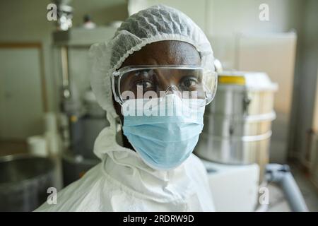 Closeup portrait of young black man wearing mask and protective suit while working at factory Stock Photo