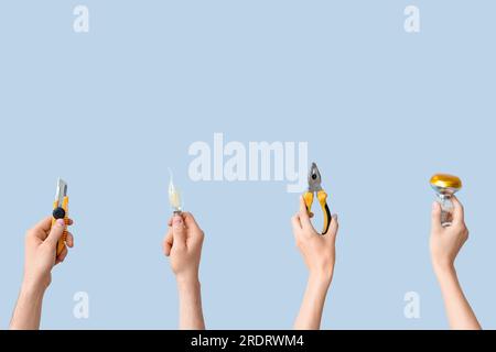 Electrician hands with light bulbs and tools on grey background Stock Photo