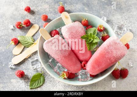 Homemade raspberry popsicles with yogurt and raspberries on a gray stone background. Ice cream. Summer dessert. Stock Photo