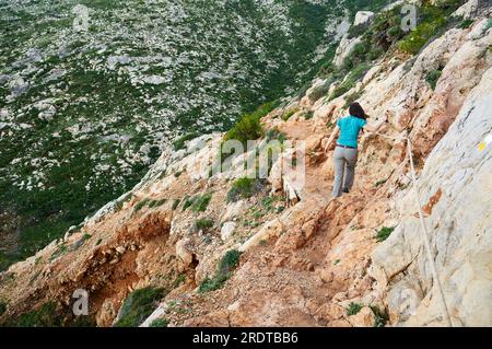 Female hiker at PR-CV 355 trail towards Cova Tallada cave (Montgó natural park, Marina Alta, Alicante, Valencian Community, Mediterranean sea, Spain) Stock Photo