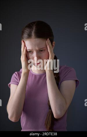 Low Key Studio Portrait Of Stressed Teenage Girl Worried About Mental Health Issues Or Bullying Stock Photo