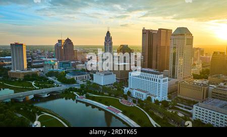 Scioto River with skyscrapers Columbus Ohio bathed in warm yellow sunrise glow aerial Stock Photo
