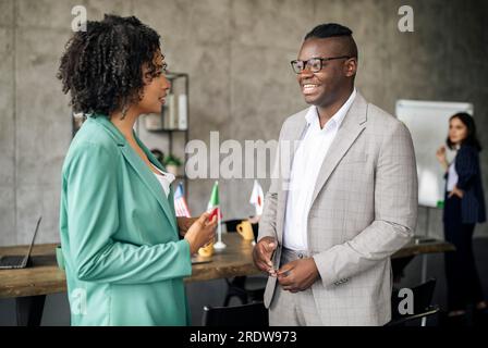 Two Diverse Colleagues Talking In Modern Office Interacting At Workplace Stock Photo
