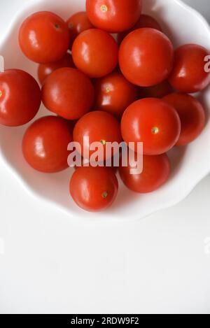 Red fruits of small tomatoes in a glass plate. Juicy cherry tomatoes. Stock Photo