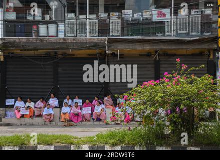 July 18, 2023, Imphal, Manipur, India: Manipuri women hold placards expressing their opinion while taking a break during a curfew. The Manipur government has imposed a one-day curfew and lifted the daily relaxation of curfew from 5 am to 6 pm in the five valley districts. The Kwairamband Ima Keithel Joint Coordinating Committee for Peace, representing women in the main market of Imphal town, has called upon all mothers to shout slogans during the ''Mothers' Protest'' rally from 11 a.m. to 1 p.m. demanding rejection of separate administration, implementation of NRC and immediate convening of th Stock Photo