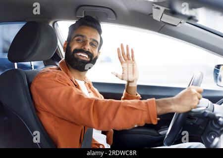 Cheerful Indian Man Gesturing Hi From Driver's Seat In Auto Stock Photo