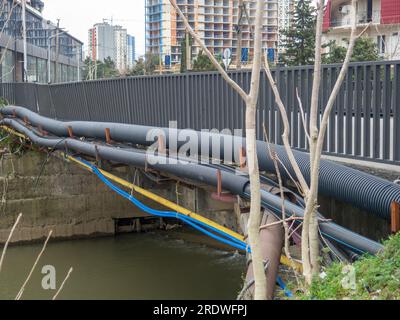 Communications go under the bridge on the river. Wires and pipes under the bridge. Gas pipeline electricity. Modern city Stock Photo