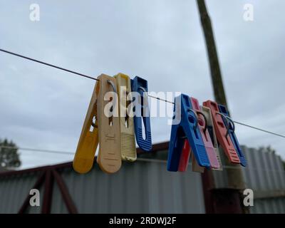 Colorful clothespins on a clothesline against the sky and grass. Stock Photo