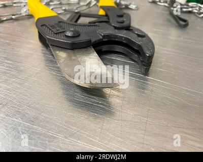 Large iron sharp metal scissors, metal cutters with chains, lie on an iron table. Hand-held locksmith tools. The background. Stock Photo