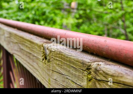 Macro close up of wood grains and split in beam with painted red pole and blurry forest background Stock Photo