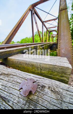 Cross shaped nail head on textured wood of distant blurred railroad bridge and tacks Stock Photo