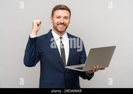 Happy sucessful business man holding laptop in hands looking at camera with victory expression.  Stock Photo