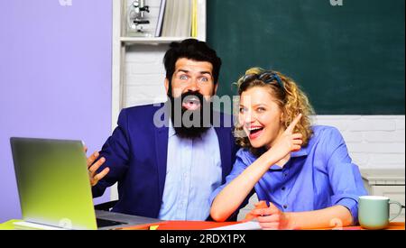 Happy female teacher with male student in classroom. Students couple studying in university college. Smiling male and female teachers at workplace Stock Photo