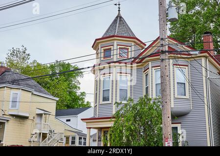 Fancy blue house with partial tower with bay windows and red trim with wind vine on roof Stock Photo