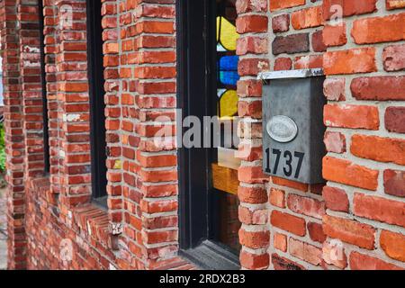 Old red brick building with protruding area around three windows and metal mailbox 1737 Stock Photo