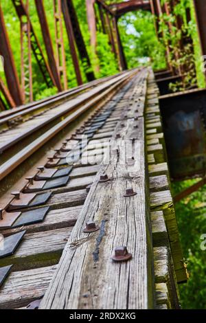 Vertical of railroad bridge with nuts and bolts on textured wooden train track beam Stock Photo