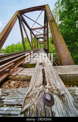 Vertical of wooden beam with nuts and bolts that spans length of truss iron railroad bridge Stock Photo