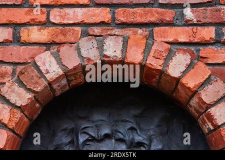 Horizontal red bricks with circular archway on bottom with partial black wavy motif Stock Photo