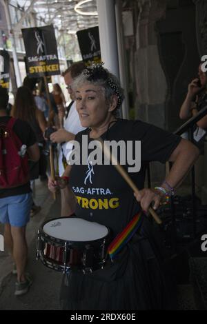 New York City: The strike continue among Writers Guild of America along with SAG-AFTRA  Union members with picket lines in multiple locations in in Manhattan. Woman beats a drum in front of Warner Bros. Stock Photo