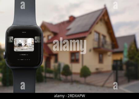 Home security system. Modern smartwatch with image of room through CCTV camera on display against house, collage design Stock Photo