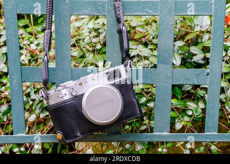 New Orleans, LA, USA - February 22, 2023: Popular Fujifilm X100V mirrorless digital camera hanging from a chair in the garden Stock Photo