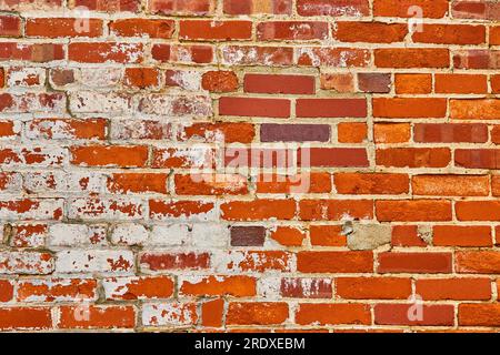 Fierce orange and red brick wall with exposed white of underlying bricks background asset Stock Photo